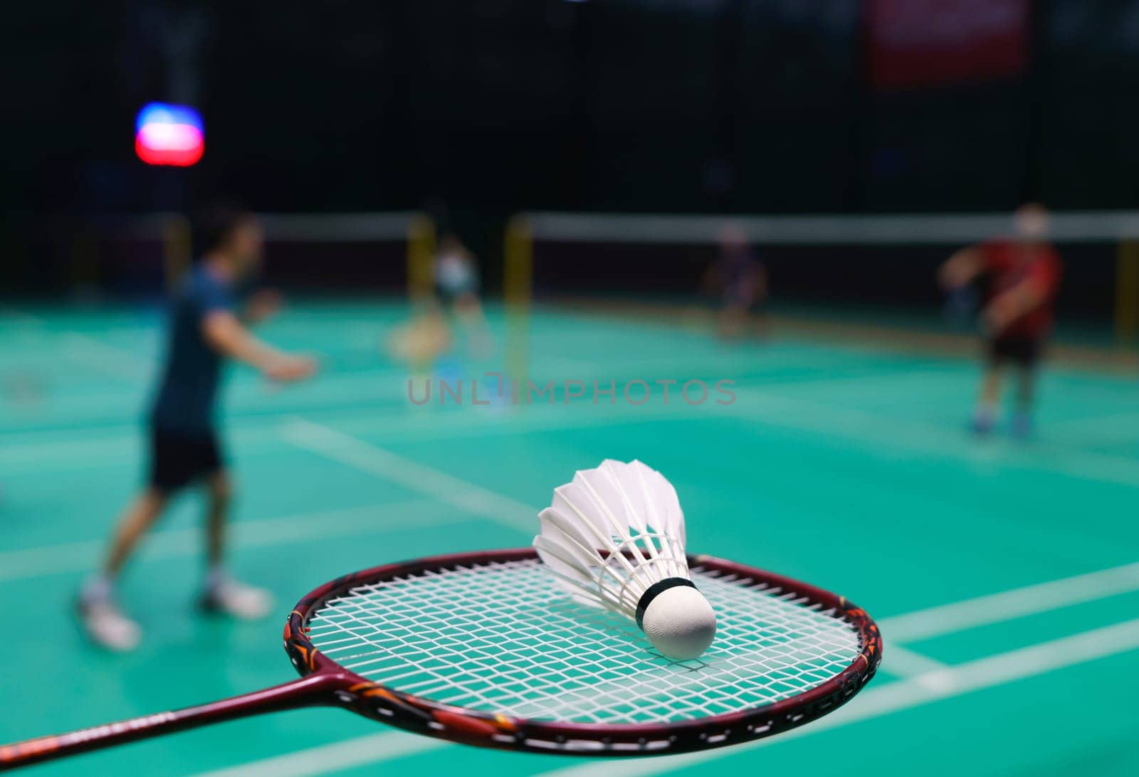 shuttlecock on green badminton playing court with player in background