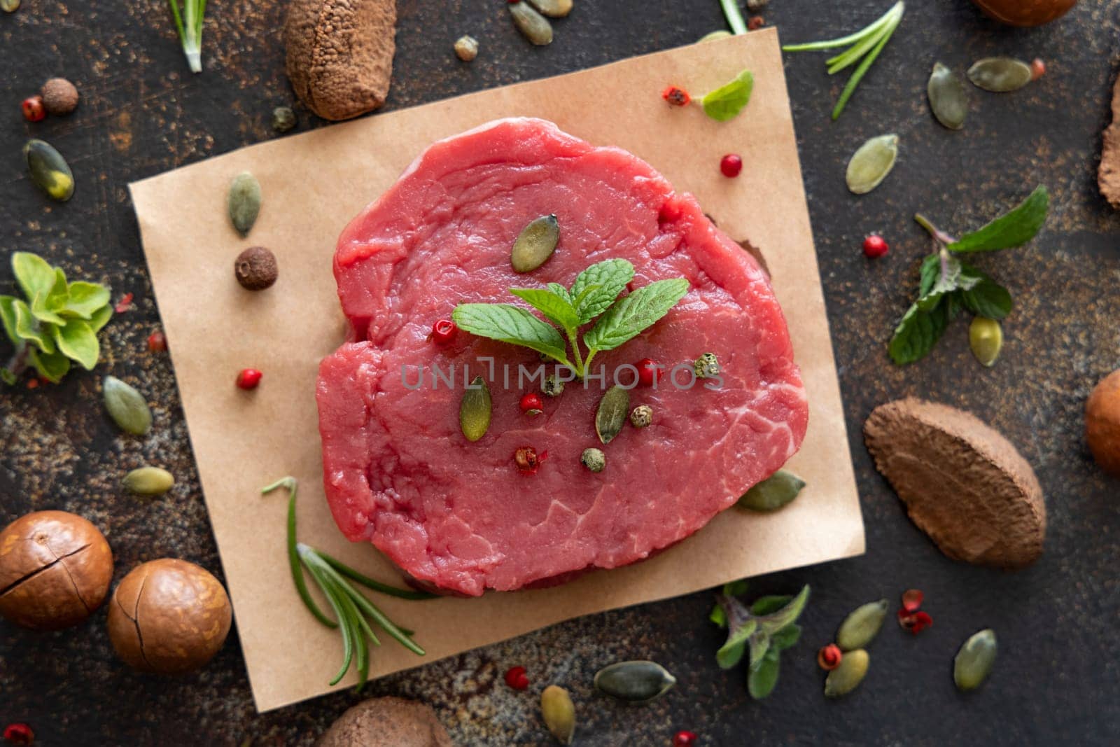 Raw beef fillet steaks on dark table top view. Portioned filet mignon with spices and herbs. Concept of summer food.