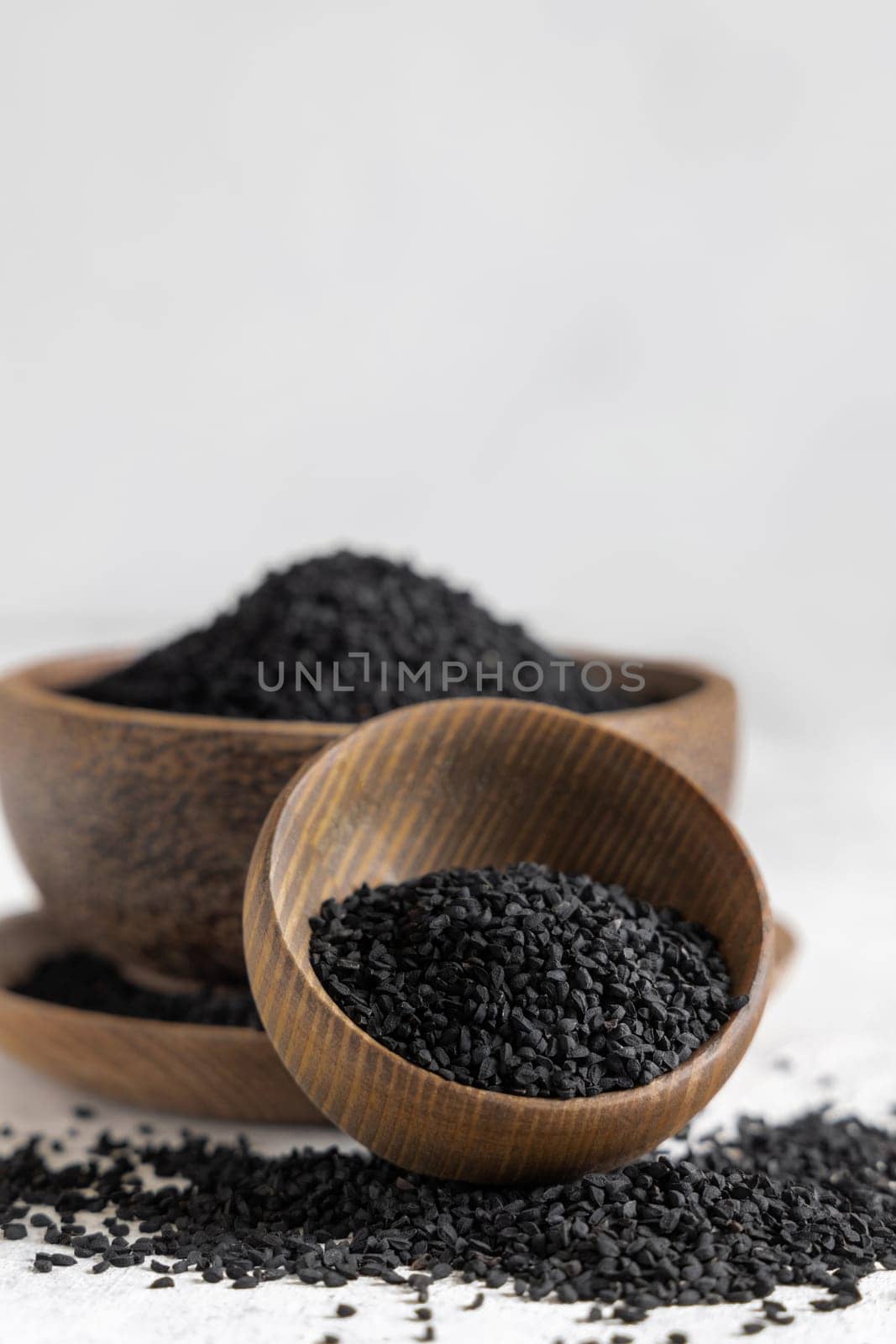 Indian spice Black cumin (nigella sativa or kalonji) seeds in wooden bowls close up with copy space. Traditional medicine, healthy and vegetarian food concept.