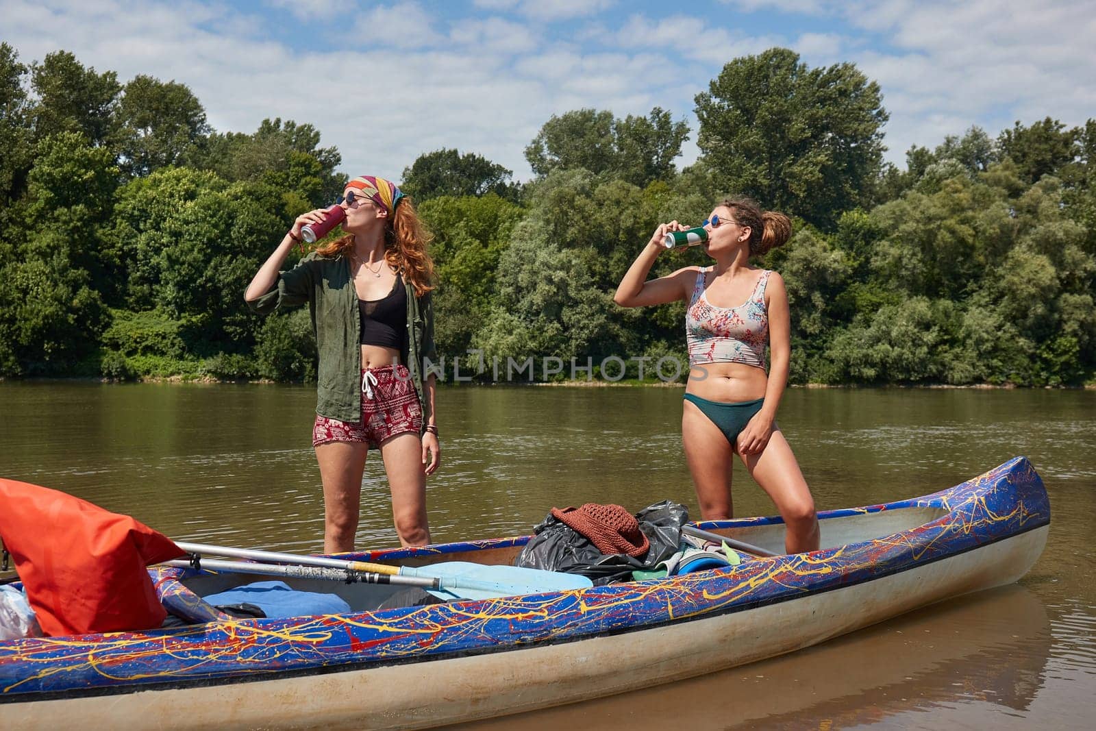 Girls standing by a canoe drinking beer in summer