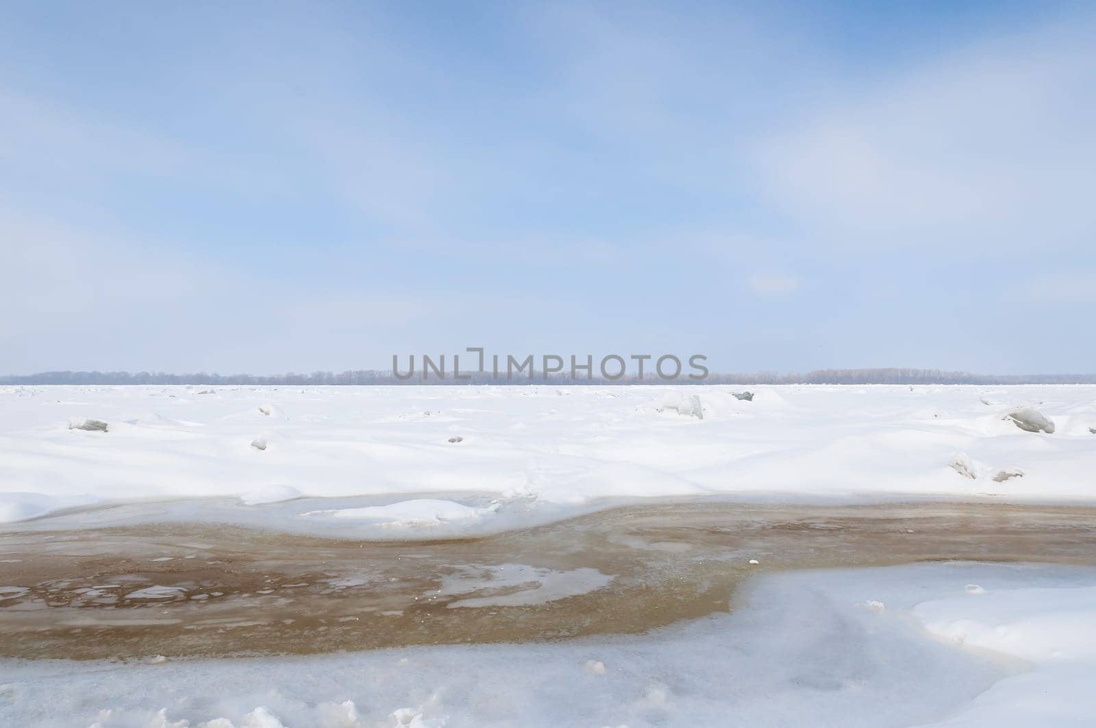 Stunning view of the frozen river covered with chunks of ice and white frosted snow. Snowy desert. The river breaks through the ice.