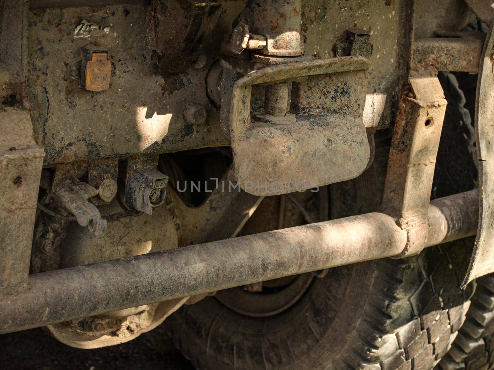 Closeup of old rusty and dirty truck back, large tire and tow mechanism visible.