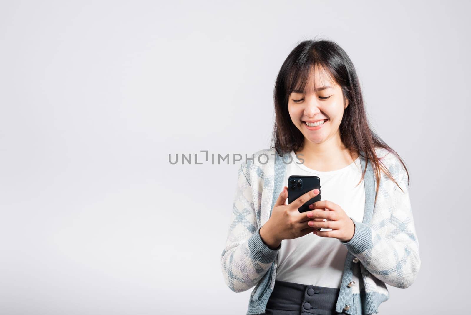 Woman excited read social network feedback on smartphone studio shot isolated white background, young female smiling typing sms message on mobile phone in social media