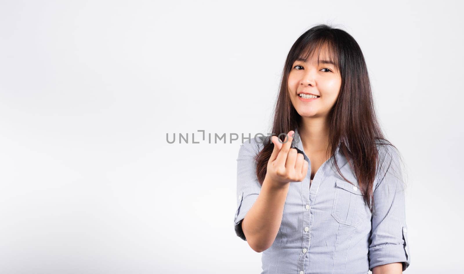 Woman standing her smile confidence showing mini heart sign with her finger isolated white background, Asian happy portrait beautiful young female send love and happy valentine in studio shot