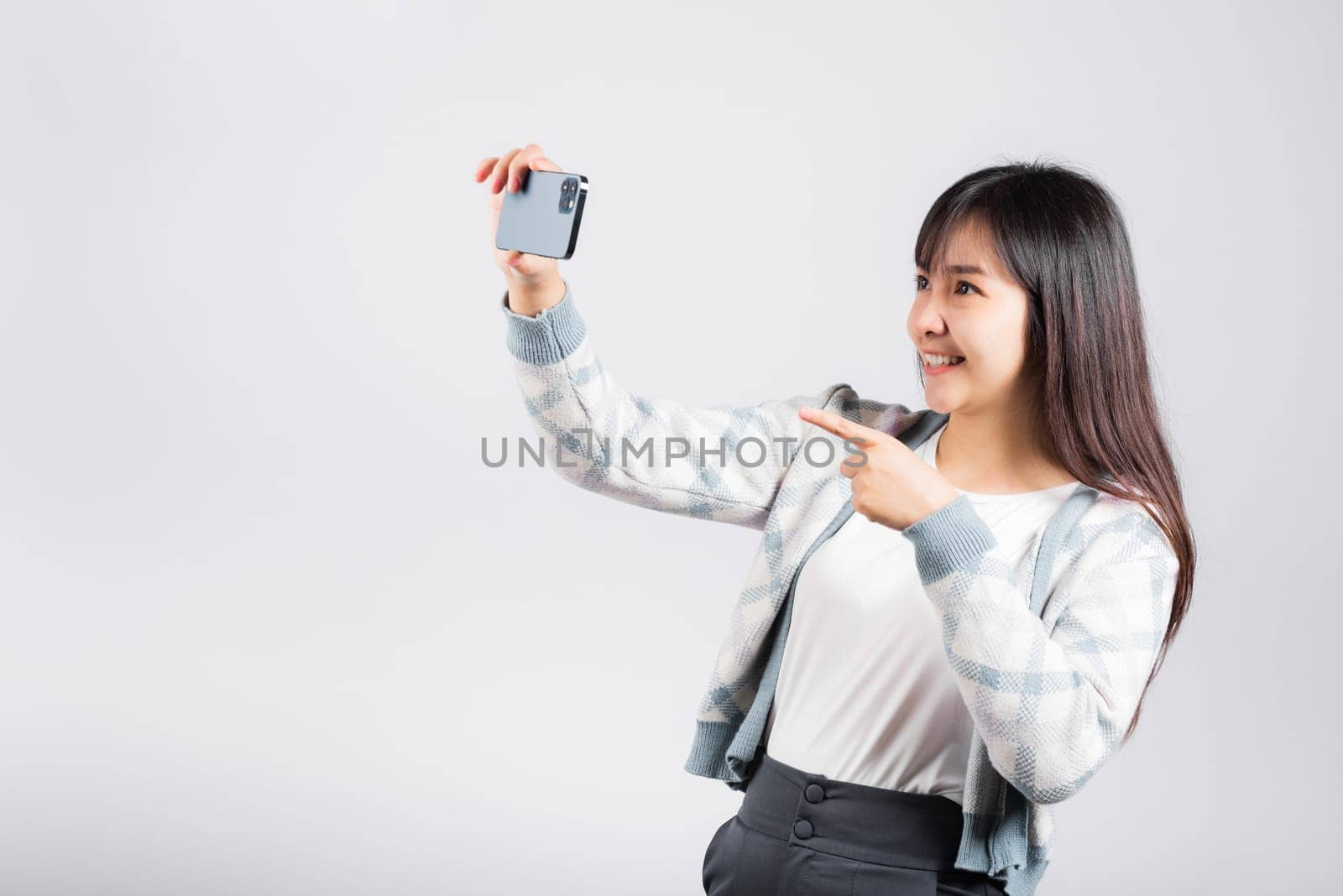 Woman excited holding smartphone to shooting selfie photo front camera studio shot isolated white background, happy young female smiling taking photography by mobile phone on mobile phone