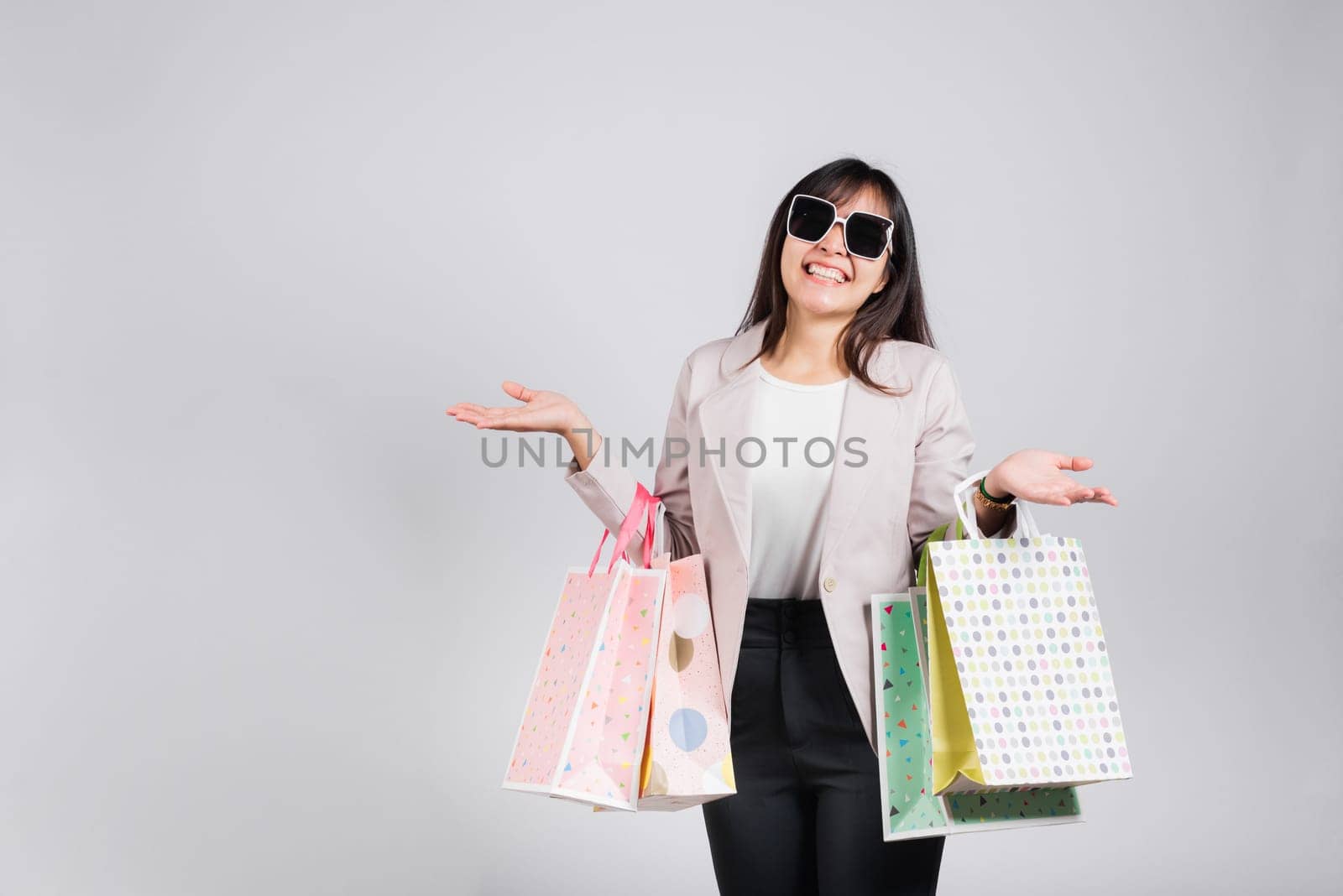 Woman with glasses confident shopper smiling holding online shopping bags colorful multicolor, Portrait excited happy Asian young female person studio shot isolated on white background, fashion sale