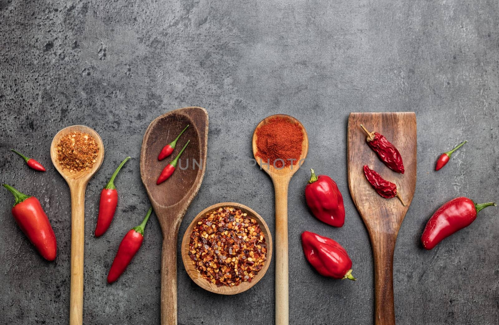Variety of fresh and dried chili peppers on rustic background