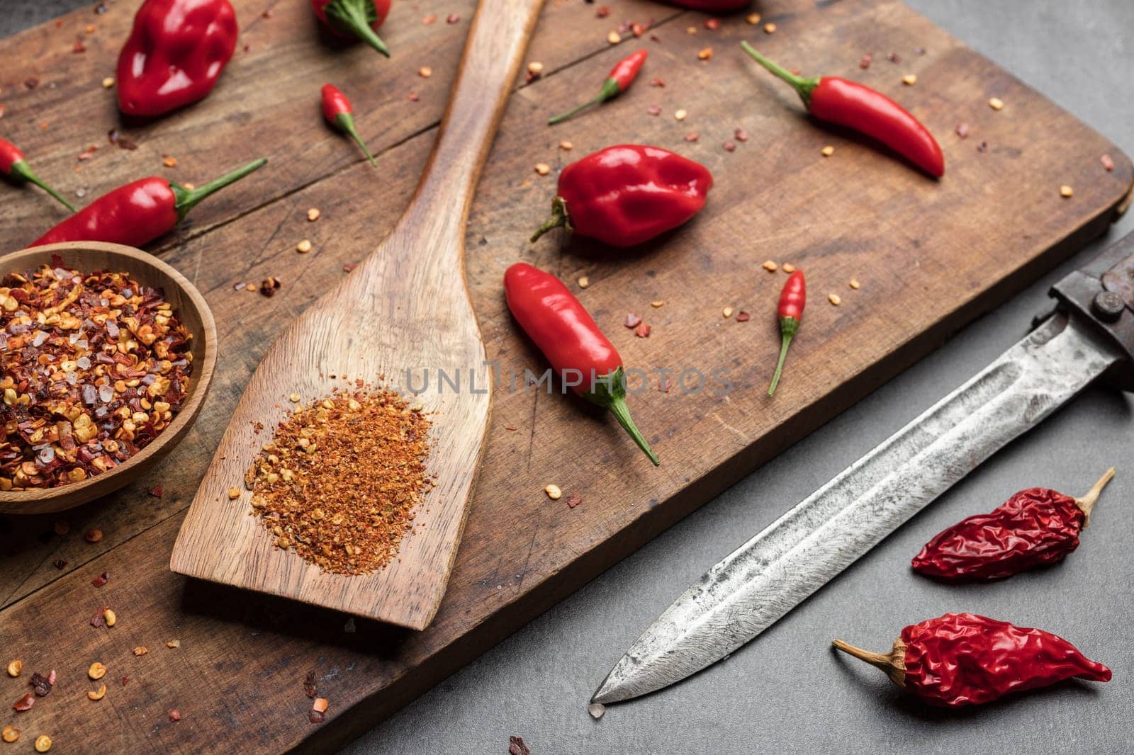 Variety of fresh and dried chili peppers on rustic background