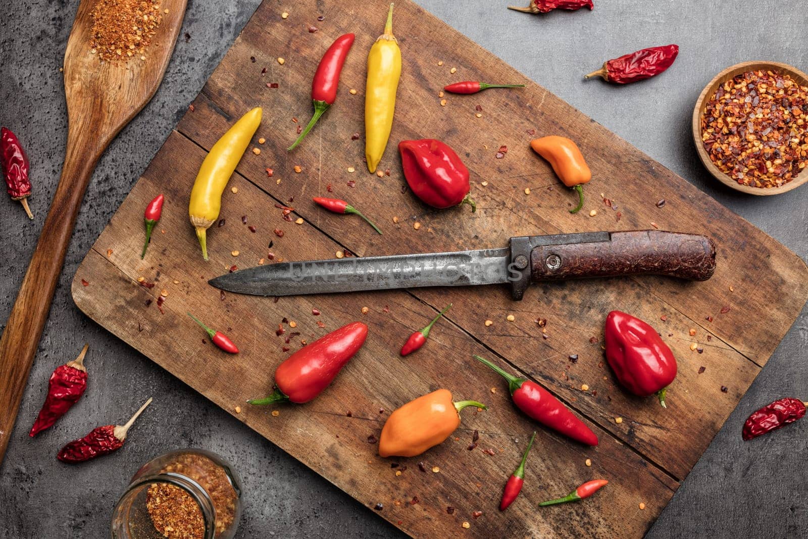 Variety of fresh and dried chili peppers on rustic background