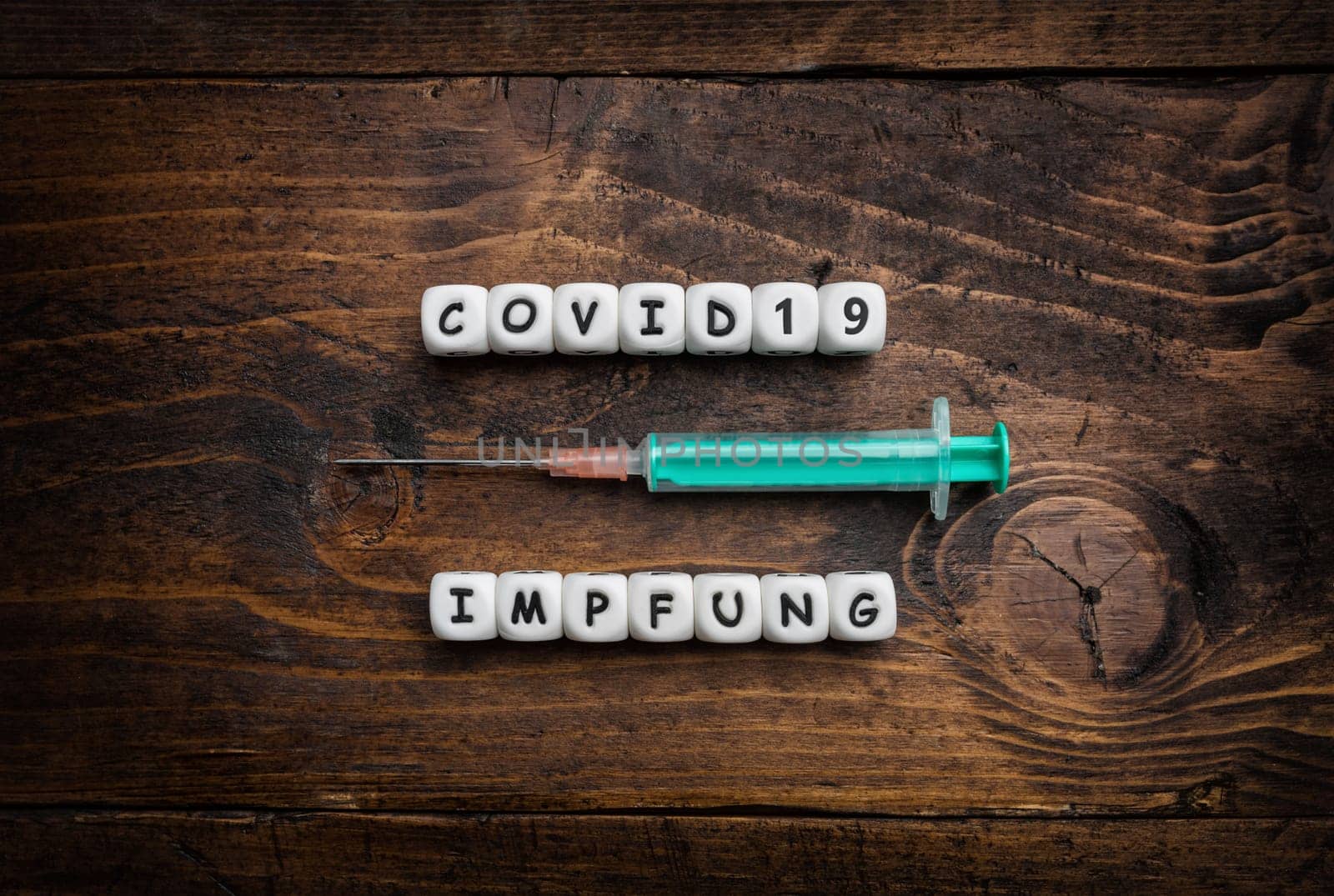 Corona virus Covid-19 vaccine text in German on wooden background