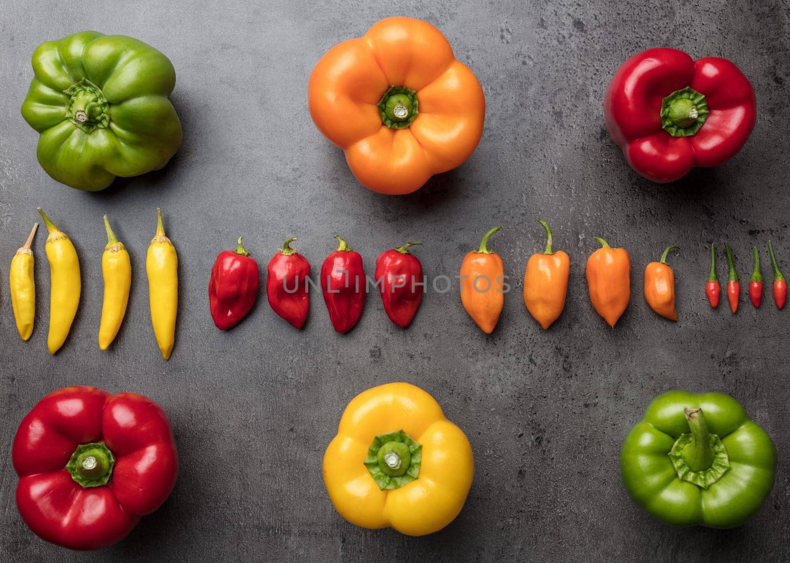 Variety of fresh and dried chili peppers on rustic background