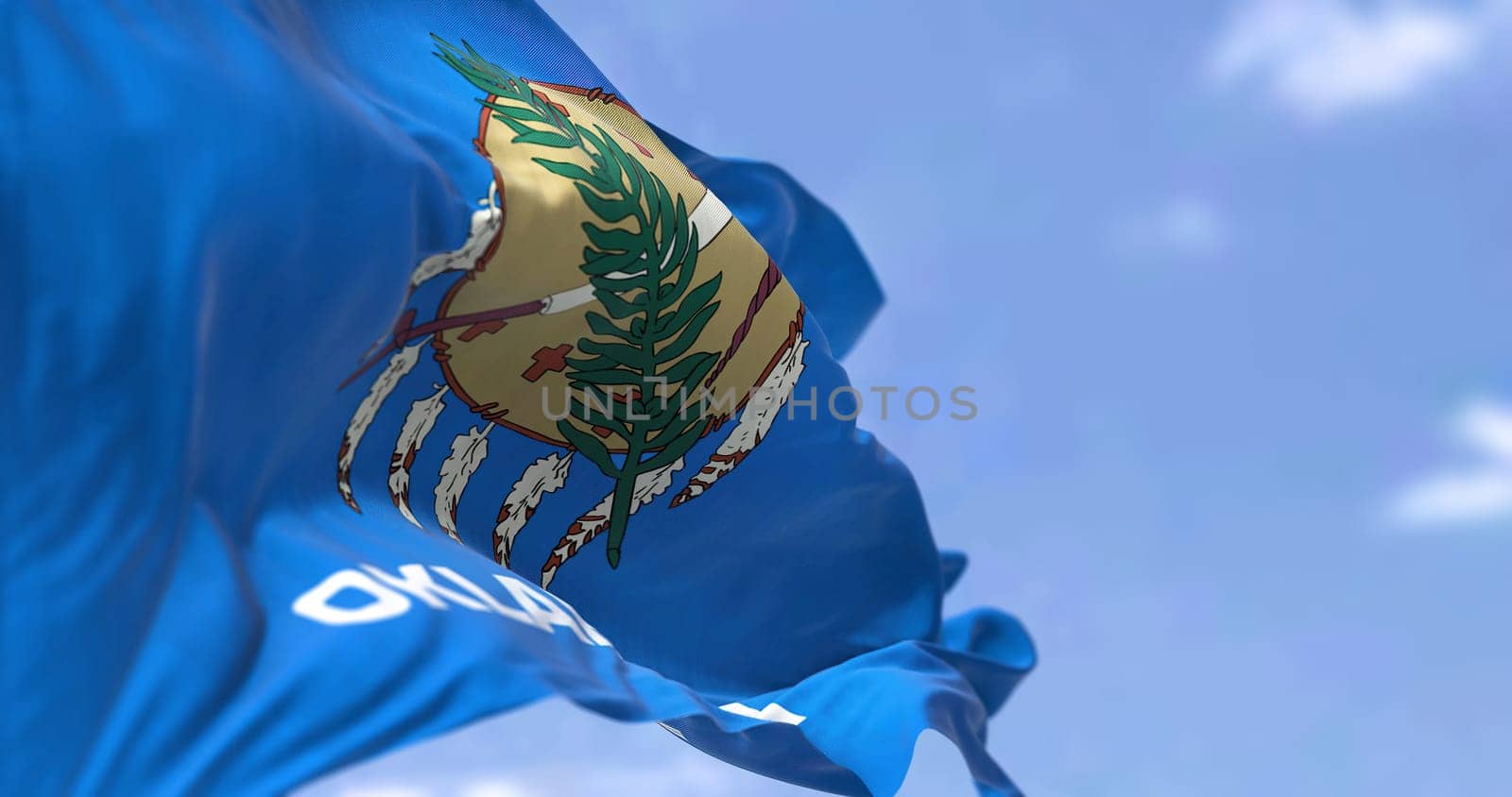The US state flag of Oklahoma waving in the wind. Oklahoma is a state in the South Central region of the United States. Democracy and independence.