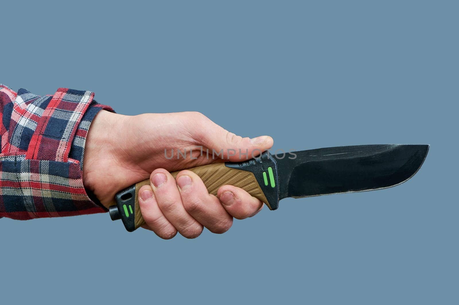 a man's hand holds a large tactical knife with a plastic handle on a gray background. High quality photo