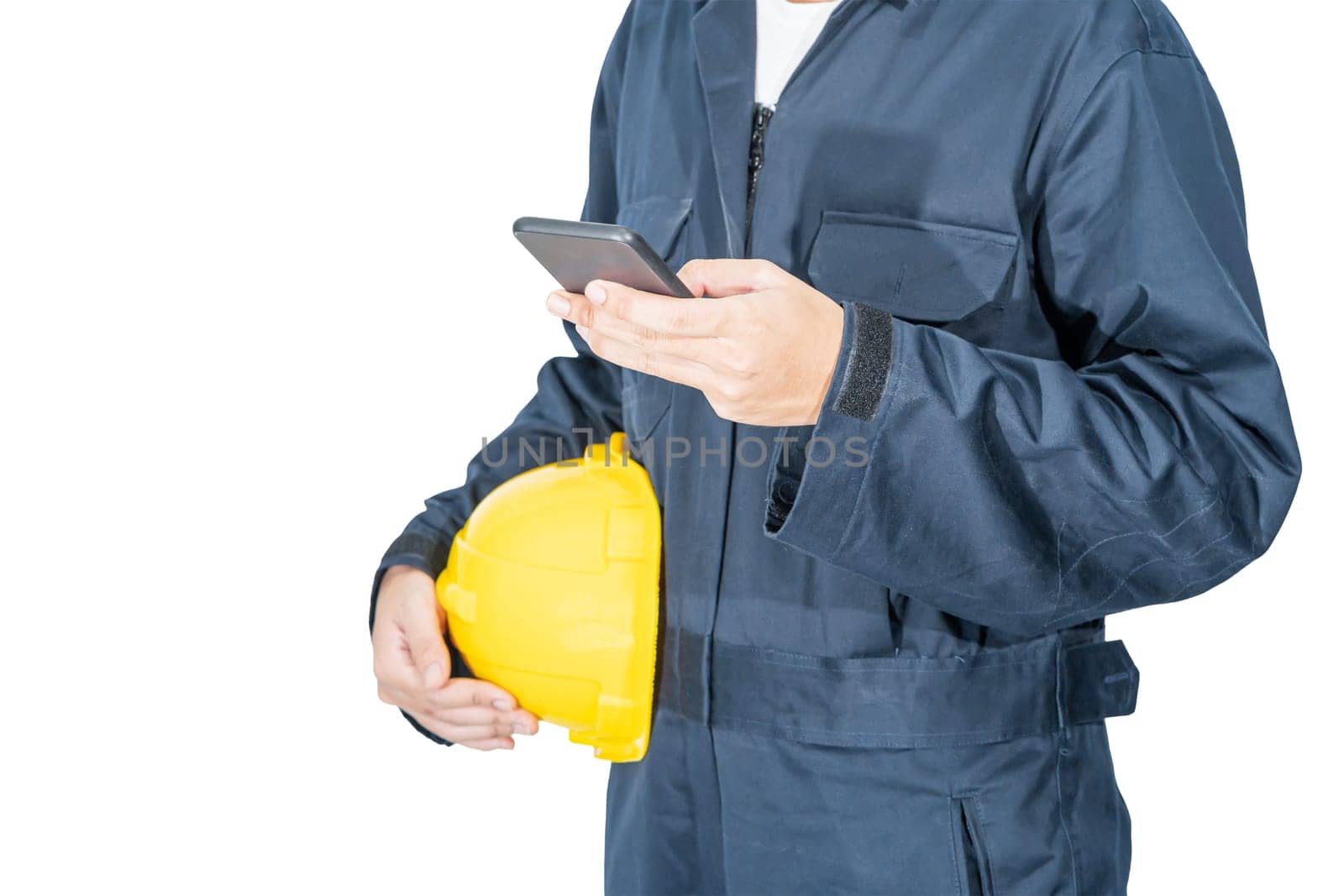 Cloes up Worker standing in blue coverall holding yellow hardhat and use smartphone isolated on white background