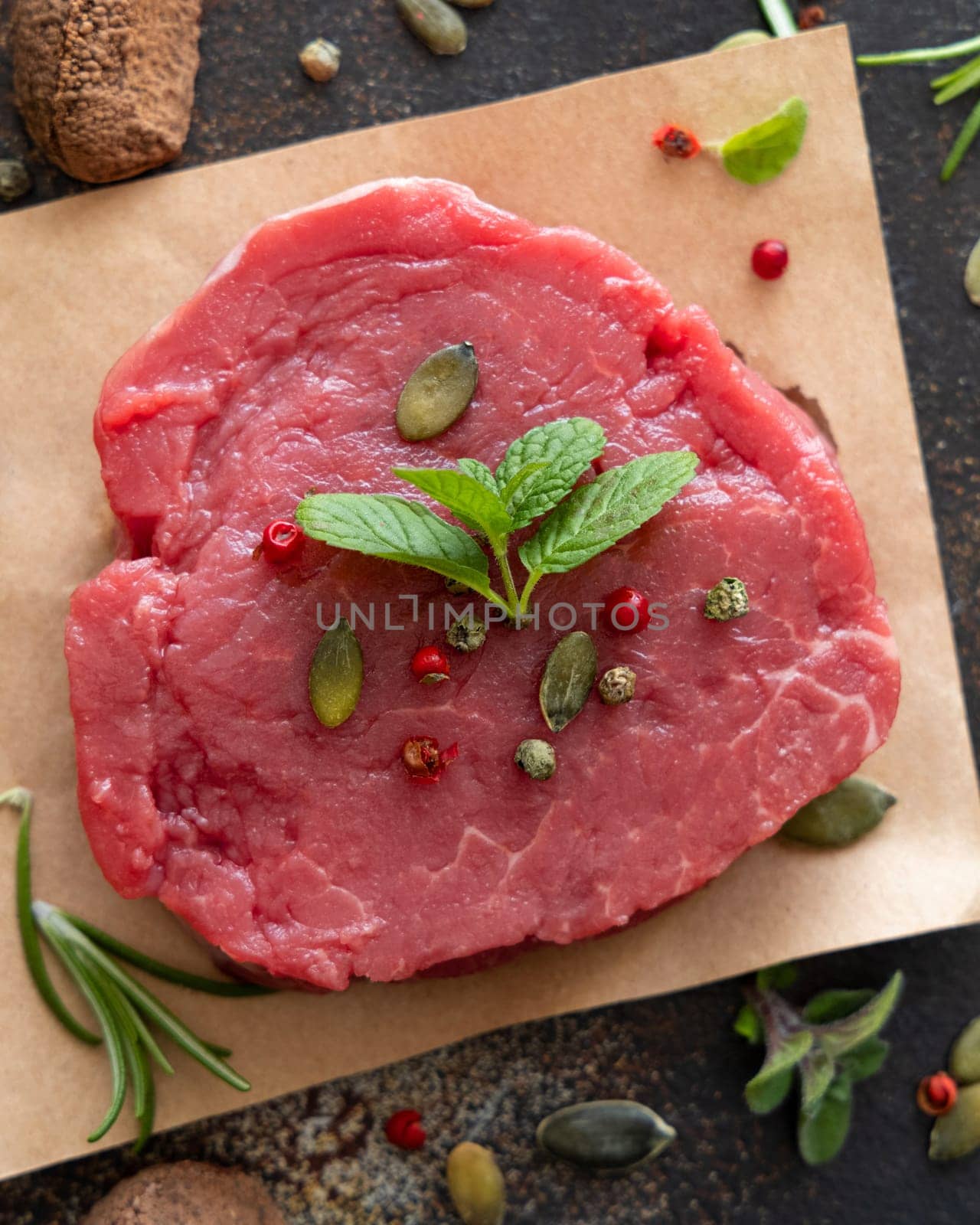 Raw beef fillet steak on dark table top view. Portioned filet mignon with spices and herbs. Concept of summer food.
