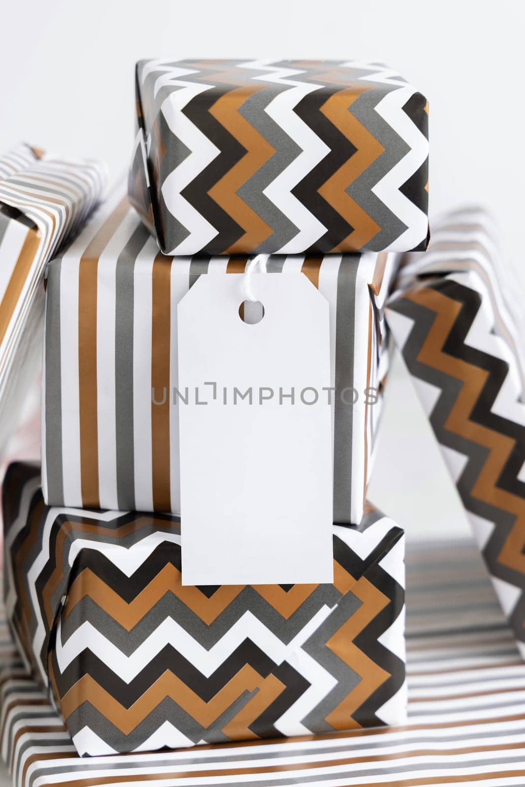 Present with blank vertical gift tag close up. Gift boxes wrapped in Striped and chevron geometric paper. Christmas, New Year, Birthday, Anniversary label mockup