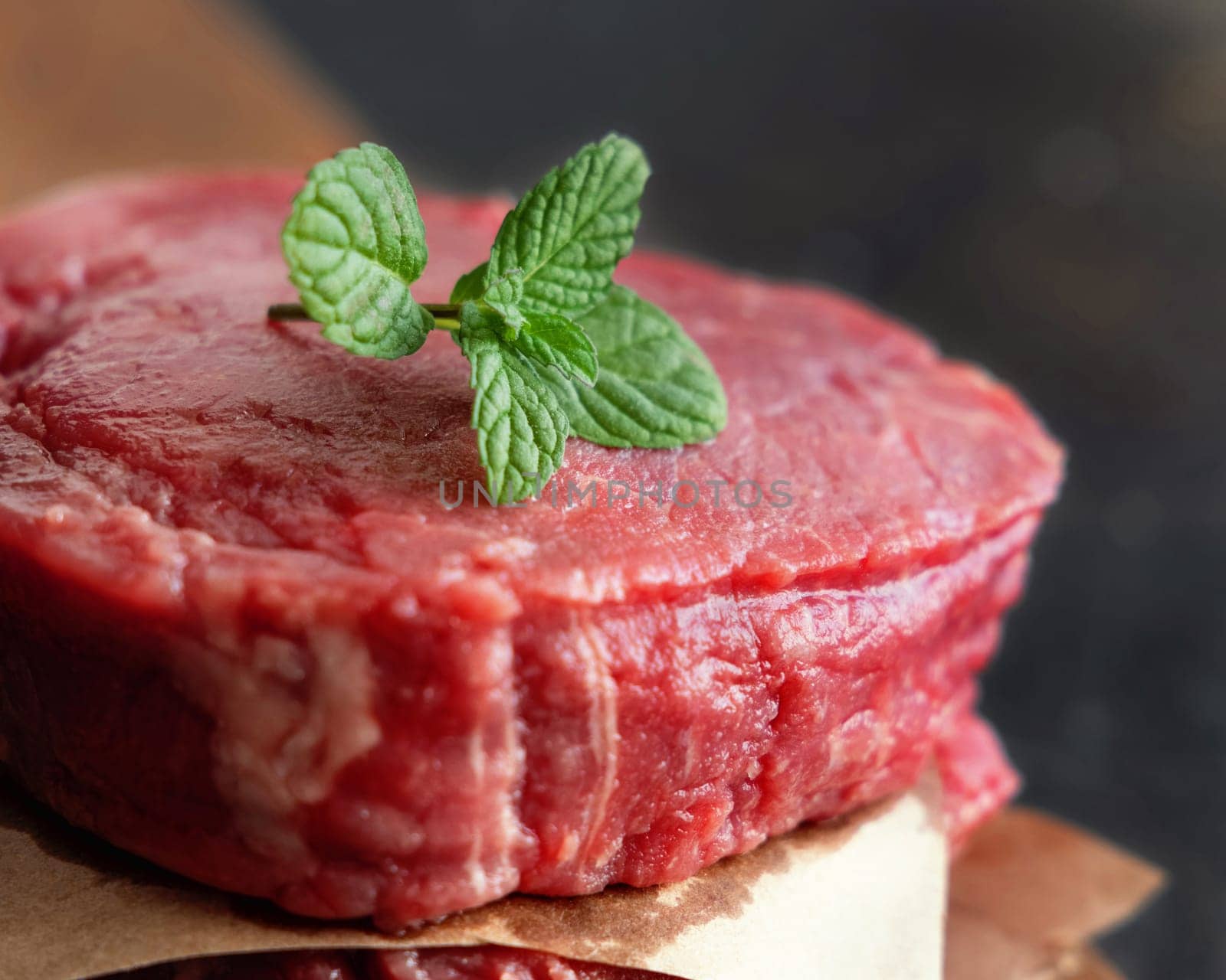 Raw beef fillet steaks on wooden board on dark background close up. Portioned filet mignons with spices and ingredients. Concept of summer food