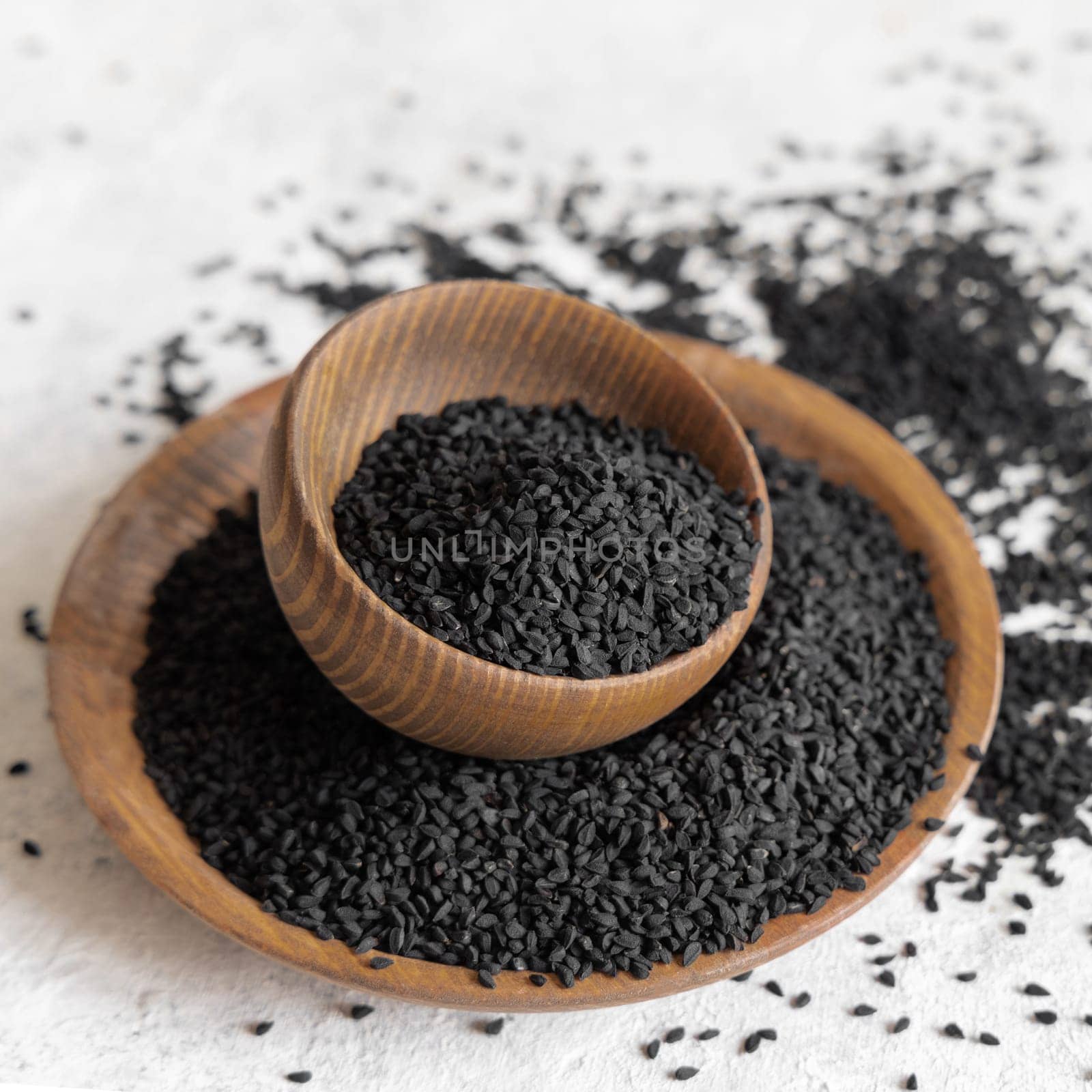 Indian spice Black cumin (nigella sativa or kalonji) seeds in wooden bowls close up. Traditional medicine, healthy and vegetarian food concept.