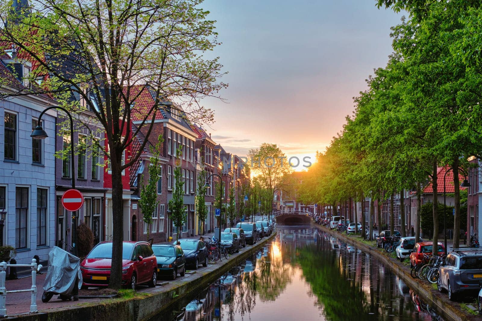 Delt canal with old houses and cars parked along on sunset. Delft, Netherlands