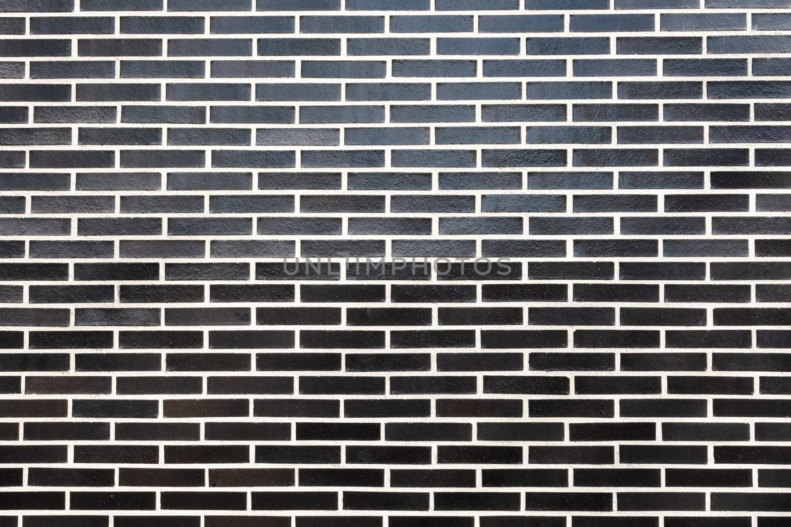 A black brick wall texture with white grout, horizontal orientation. Great seamless background for different purposes, copy space for text.