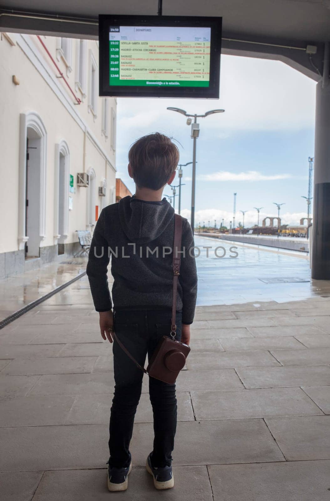 Child boy at railway station looking to departure monitor. Travel on train with children concept