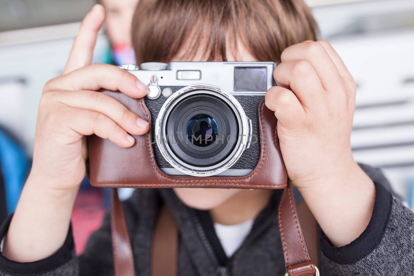Child boy taking pictures with retro camera. He is about to press the shutter