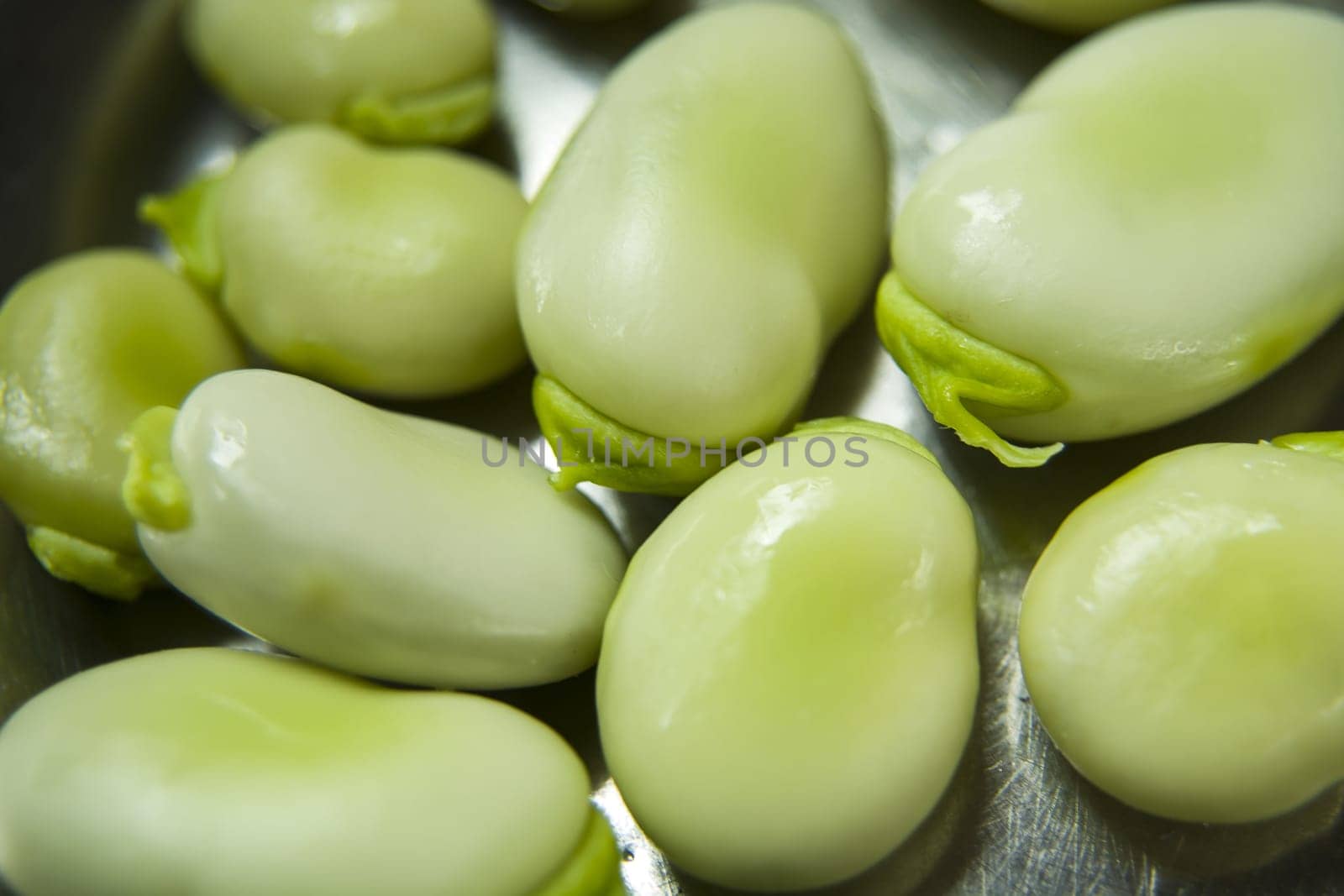 Raw green fava beans close-up on a silver board
