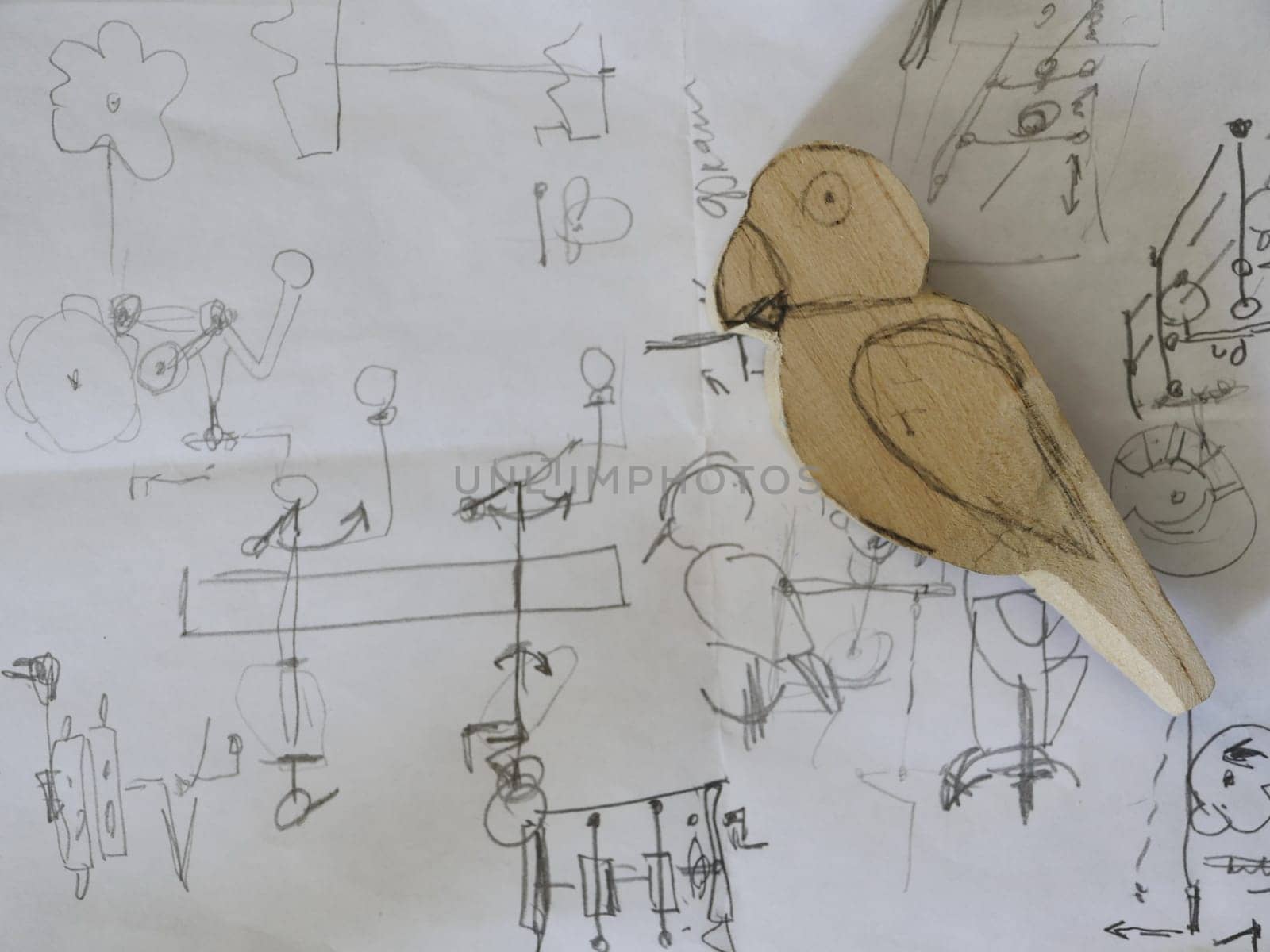 Parrot drawing with a pencil on paper and a wooden figurine of a parrot