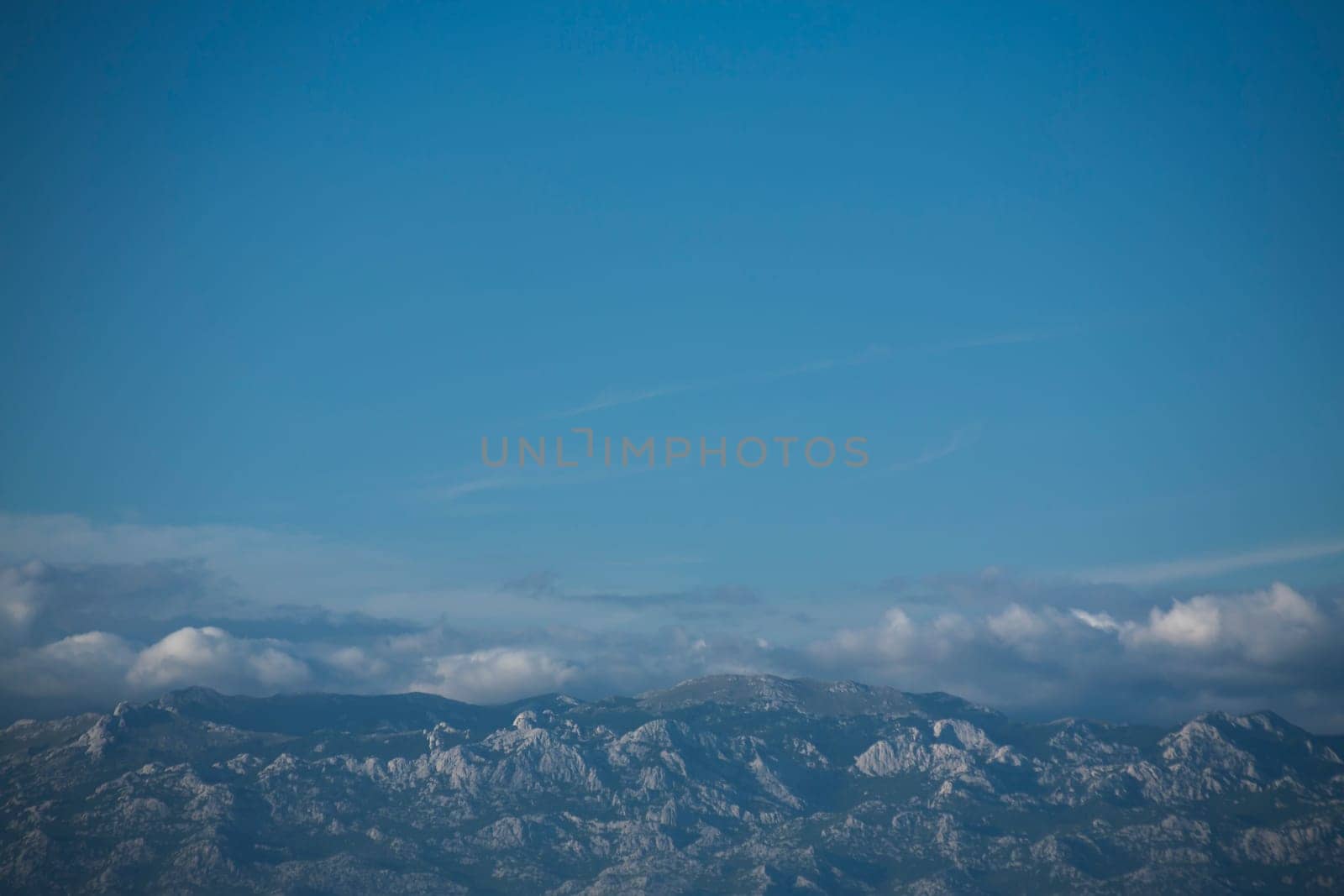 Blue skies and Velebit mountain peaks below. Copy space.