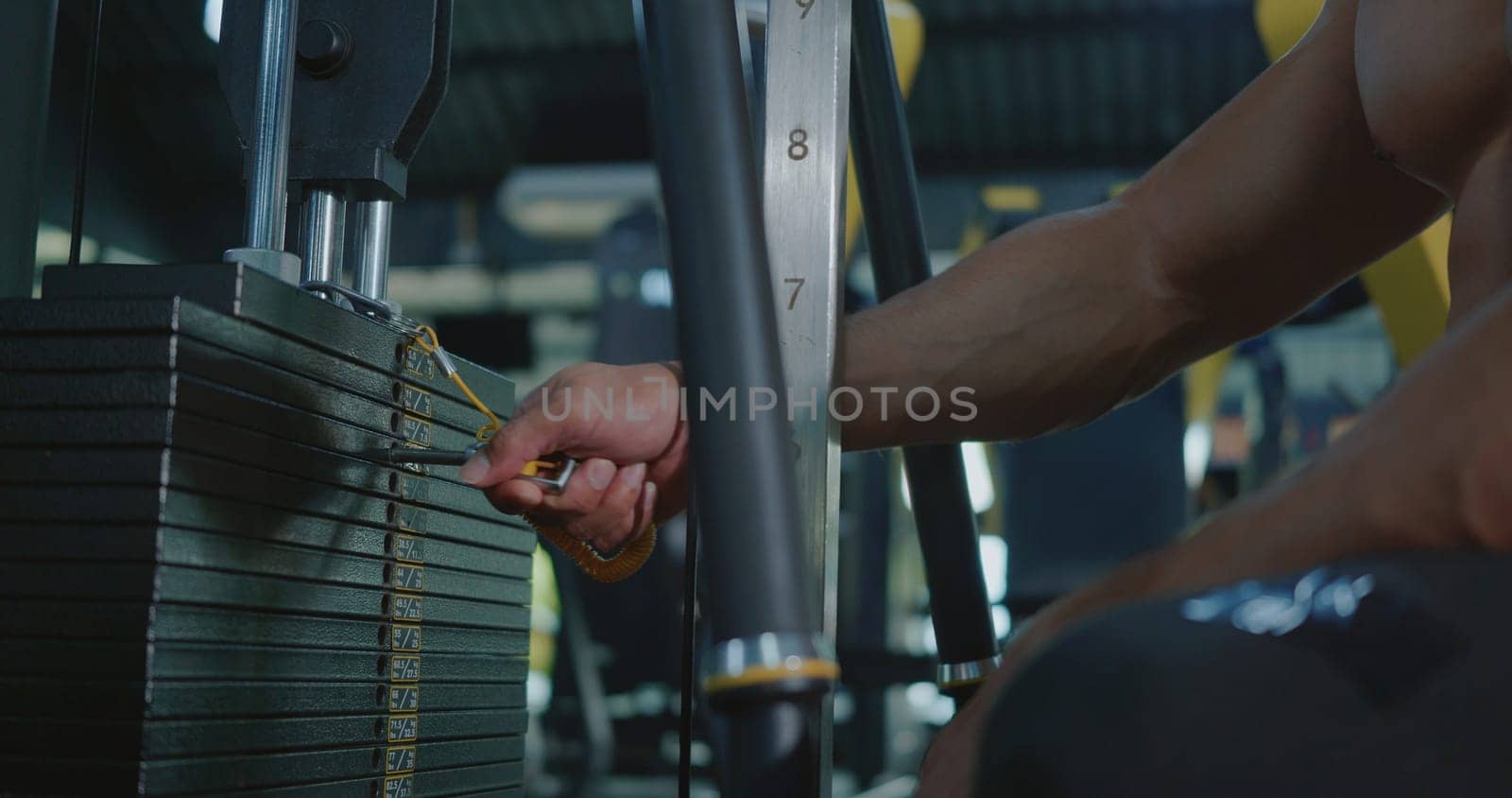 Closeup hands of athlete man chooses weight in the sports equipment in exercise machine, muscle sportsman choosing different weightlifting options for lifting training workout at fitness gym