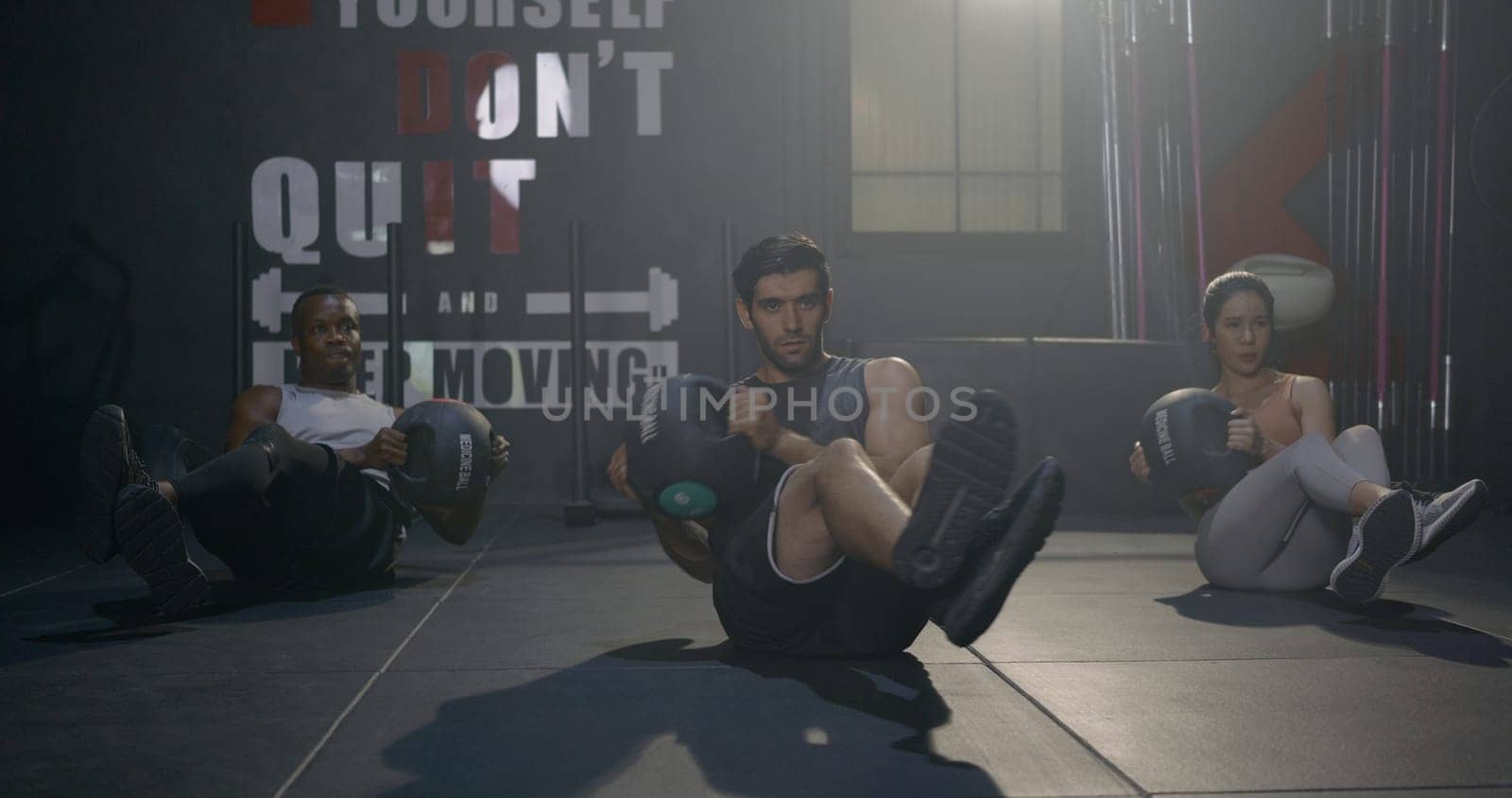 Young muscular athletic group doing training abdomen exercises working out with a medicine ball in fitness gym, strength workout healthy lifestyle sport concept