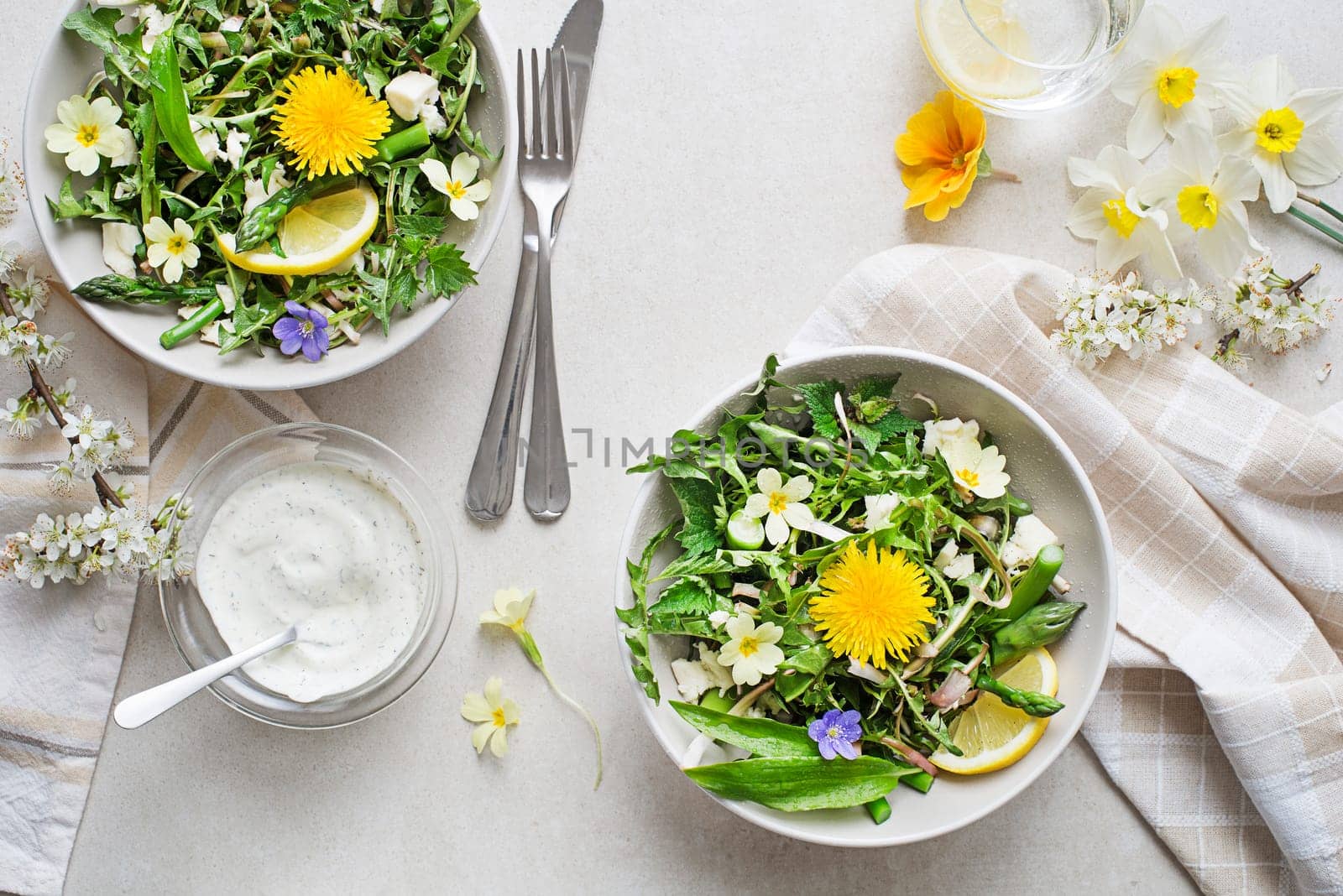 Spring salad with dandelion, asparagus, flowers, nettle and cream cheese. Healthy spring detox food ingredients.