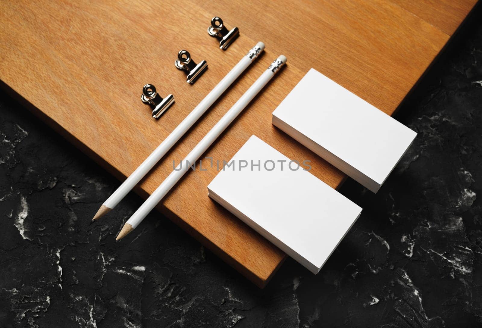 Blank branding stationery. Blank business cards, pencils and clips on wooden board background.
