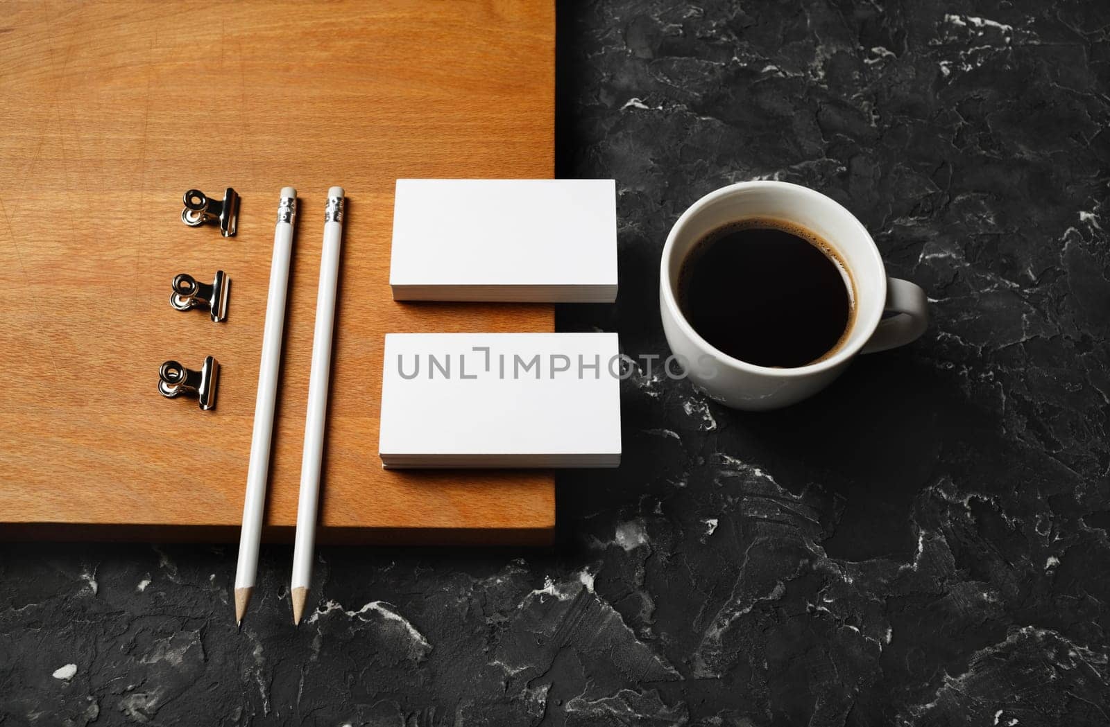 Coffee cup, blank stationery: business cards, pencils, metal clips and wooden board. Objects for placing your design.
