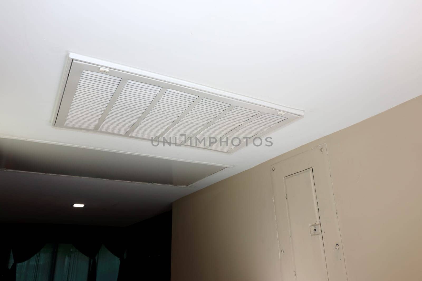 In a home ceiling indoors is a white rectangle air return vent as part of a HVAC system. Large white rectangle ceiling air return vent to a duct indoors in a home that helps to ventilate the home