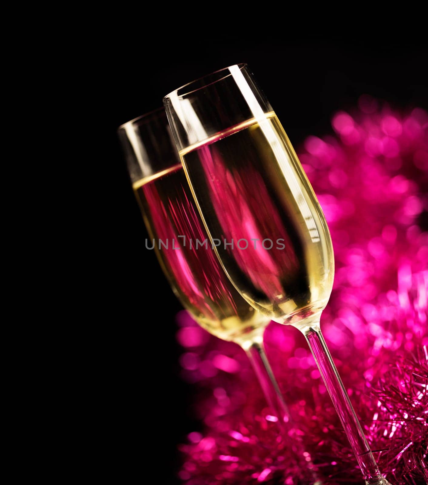 Two champagne glasses in front of purple sparkling background