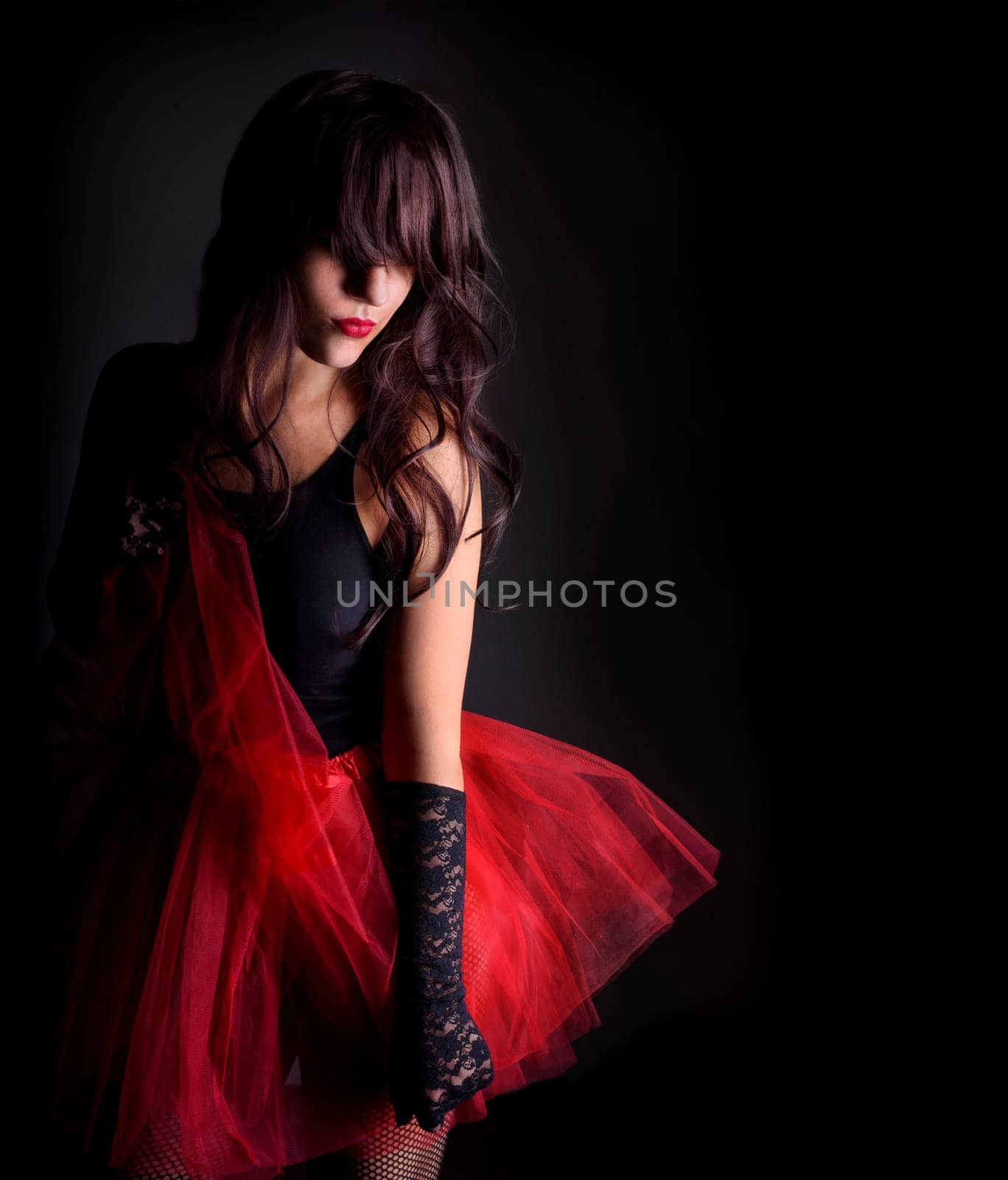 Sexy young woman in red dress against black background
