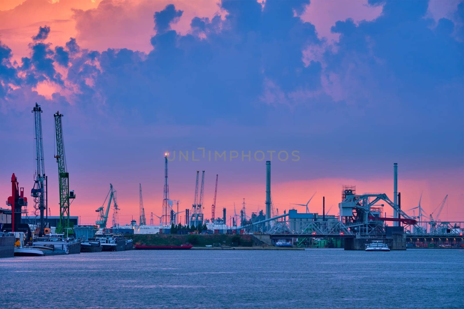 Port of Antwerp with harbor cranes in twilight and a ship passing under brigde Antwerp, Belgium