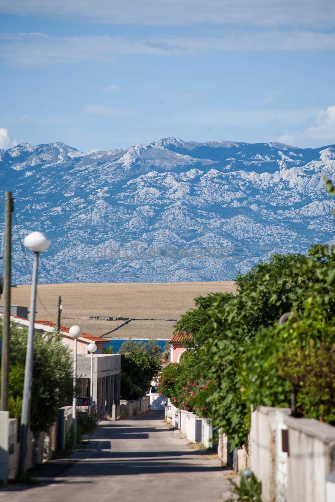 A small alley towards the sea in the apartment complex Lučica on the island of Vir, Croatia. View of the sea and the mountains.