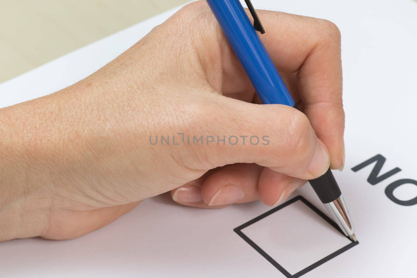 Female hand is holding a blue pen and is ready to fill NO in the printed form.