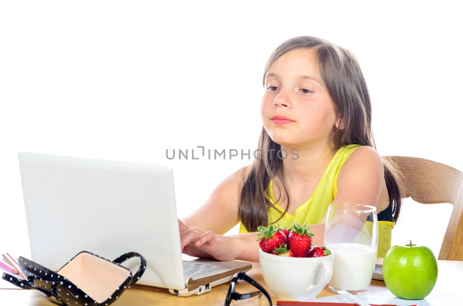 a little girl doing her homework on her computer on white