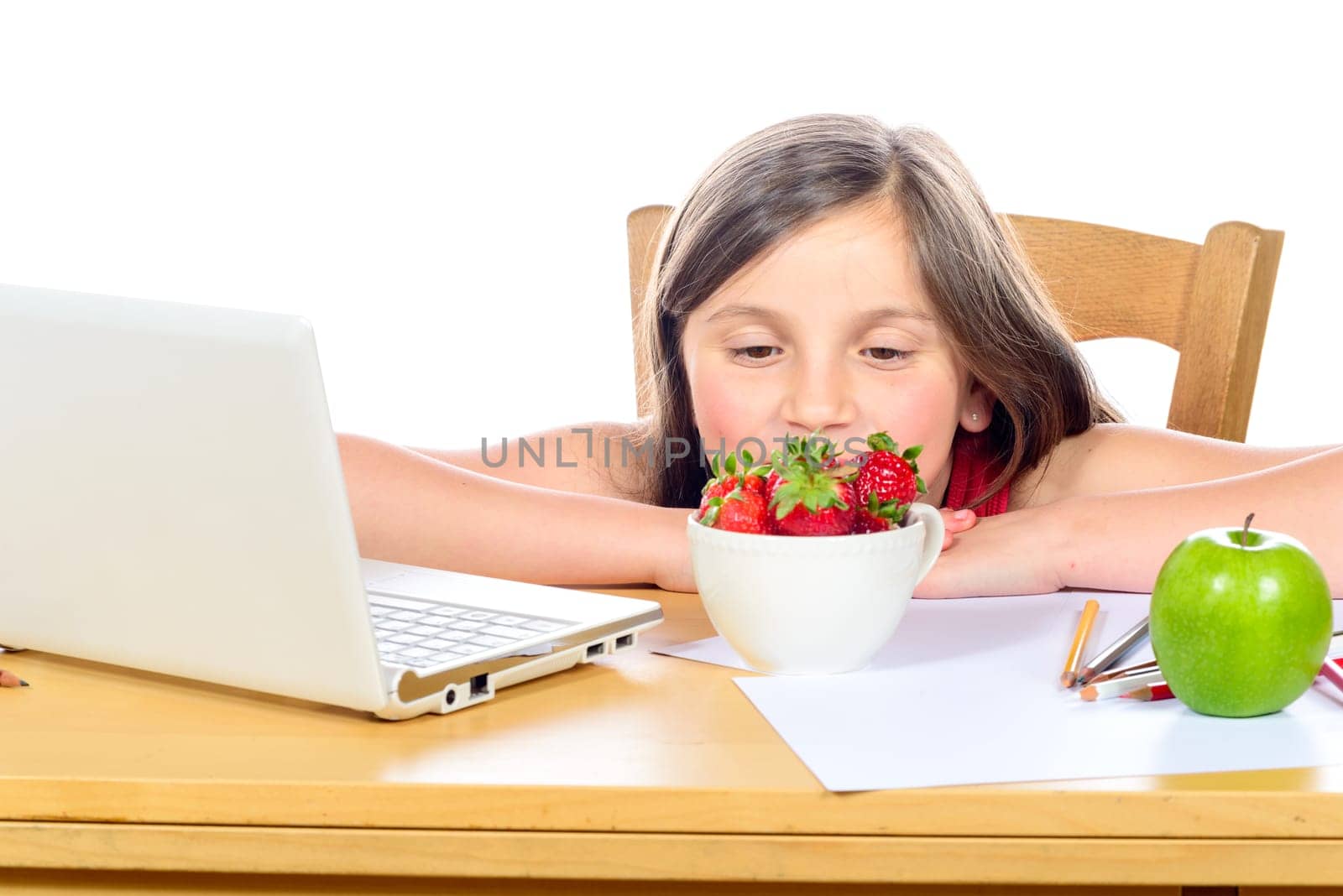 a little girl sitting at his desk with a bowl of strawberries and apple