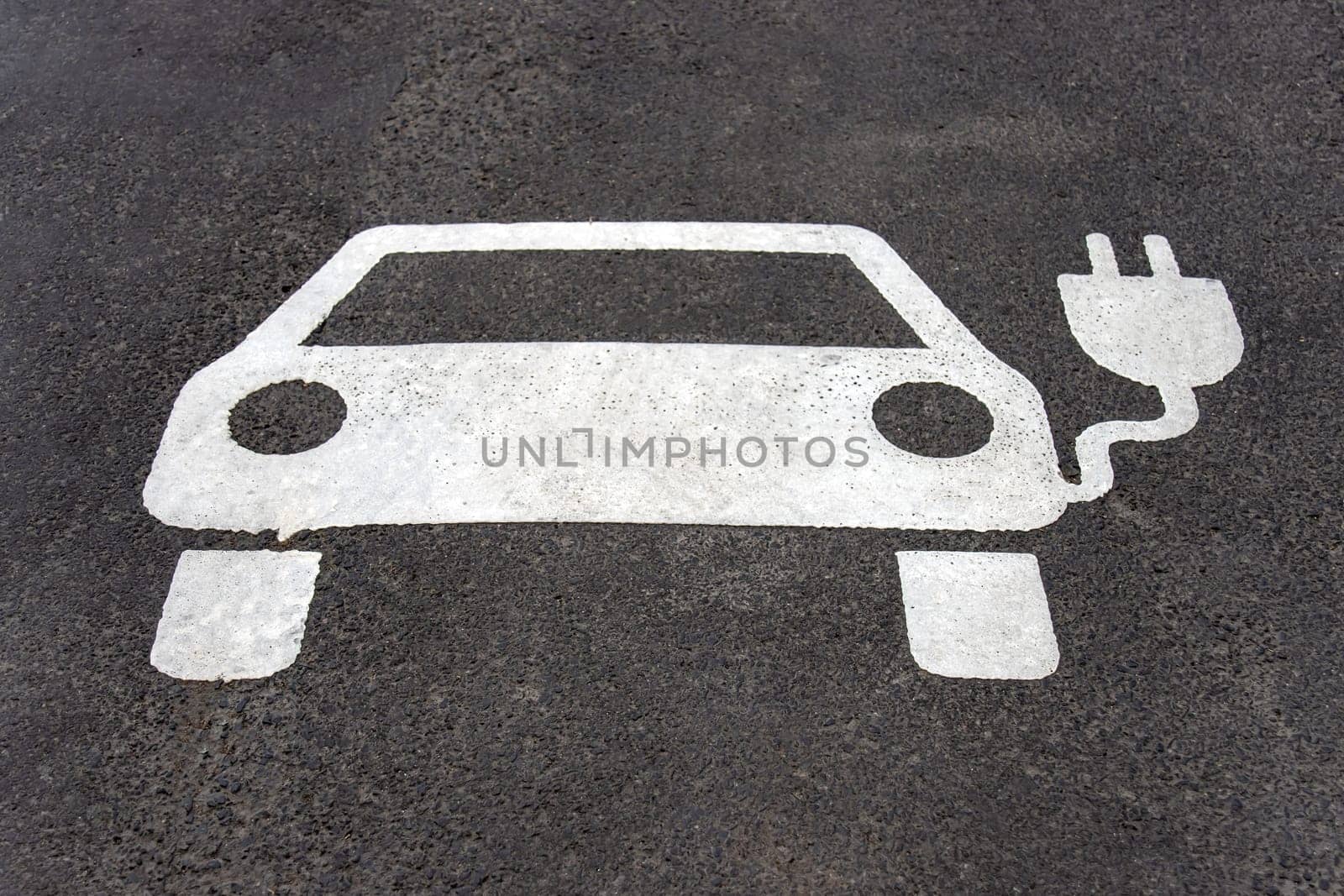 Parking space reserved for electric car. Asphalt marked with a car and plug.