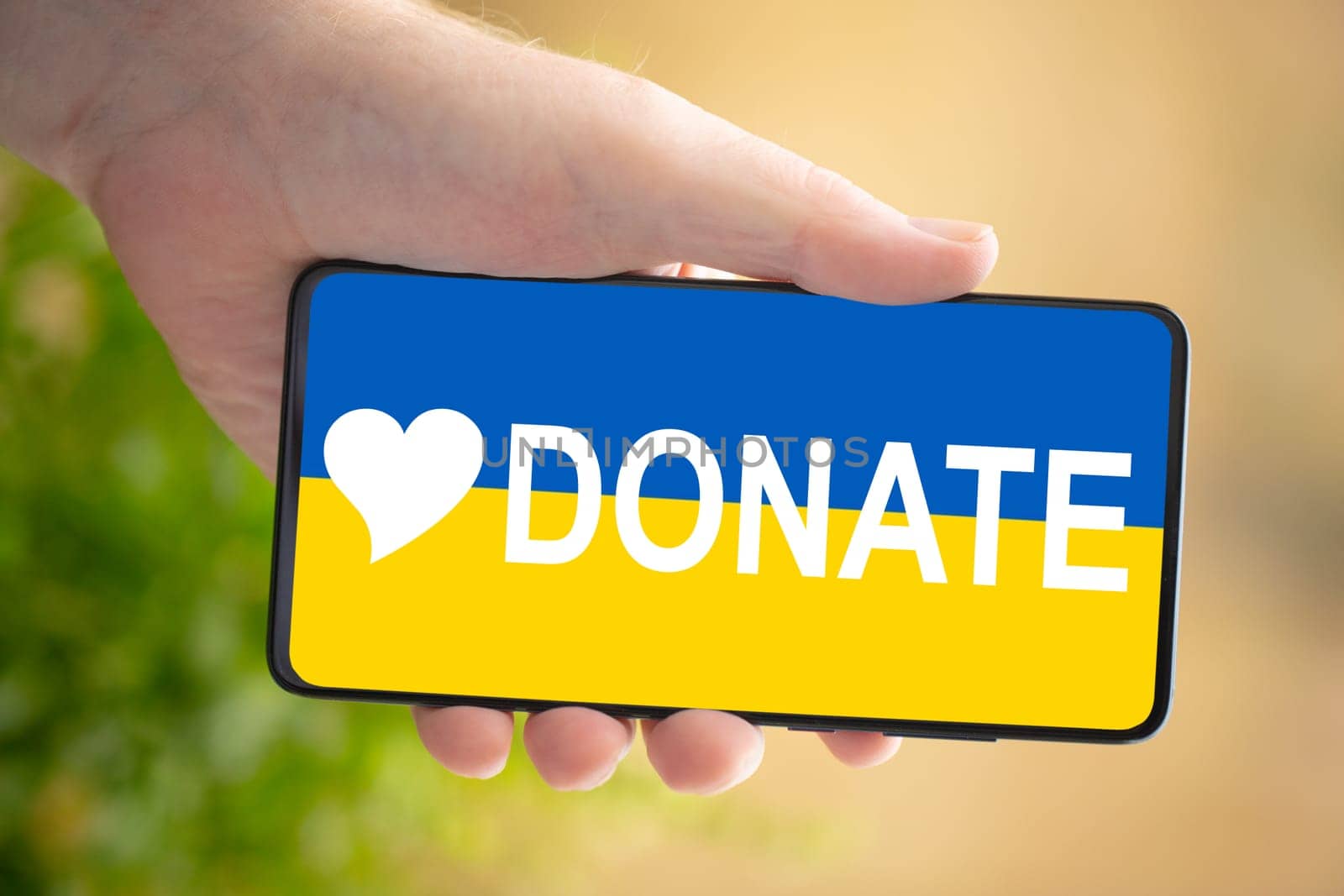 Male hand hold a cellphone - conceptual for donate and support for Ukraine.