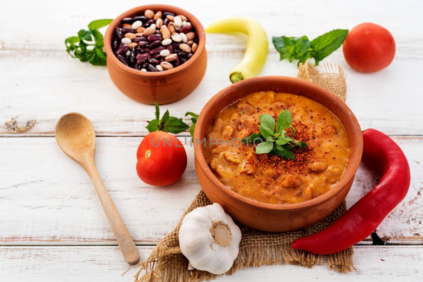 Spicy baked beans in traditional clay pot.