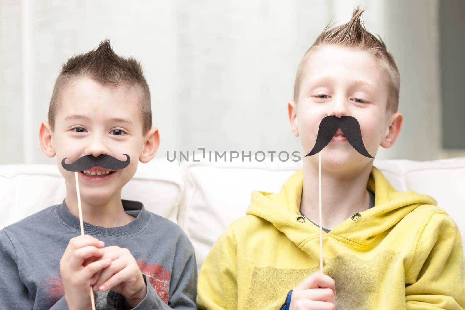 couple of little brothers making funny faces with fake moustaches