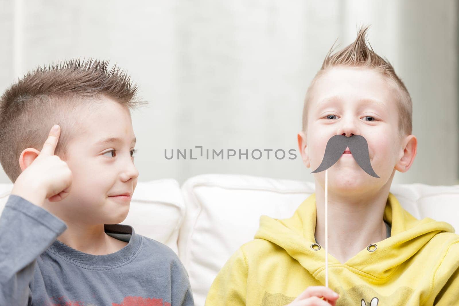 couple of little brothers making funny faces with fake moustaches