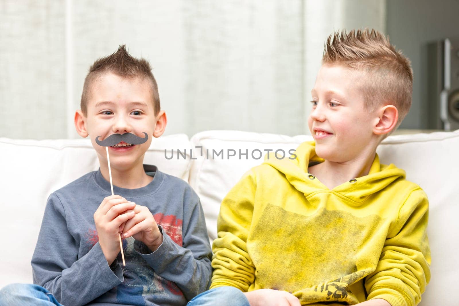 couple of little brothers making funny faces with fake moustaches