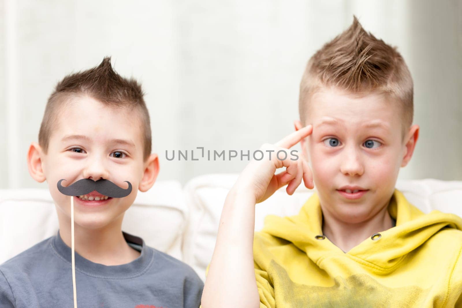 couple of little brothers making funny faces with fake moustaches