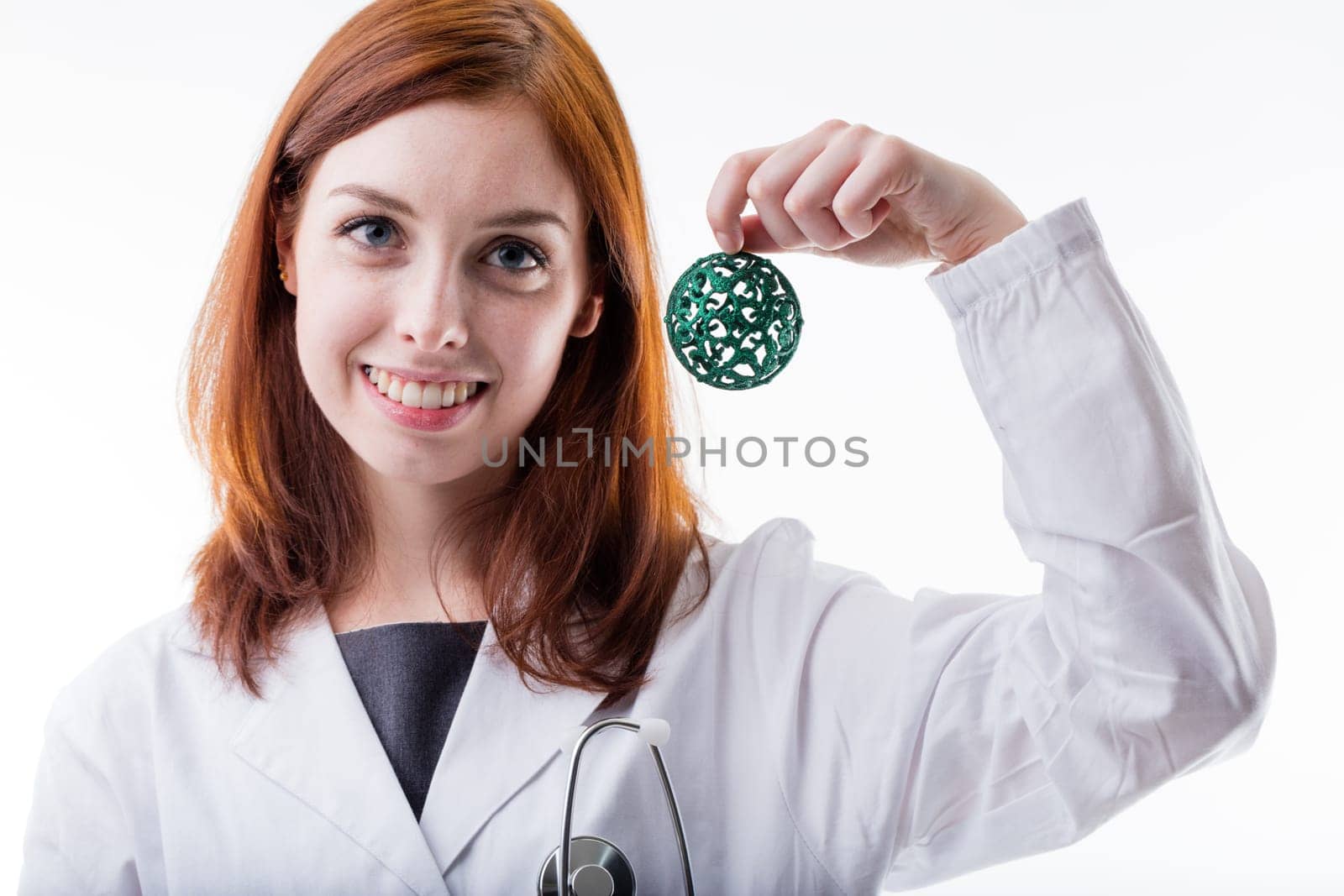 red haired woman is a medical doctor holding a christmas ball to celebrate with patients or to promote an initiative in favor of unlucky people